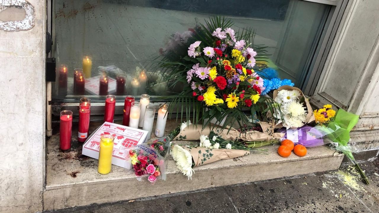 Flowers, candles and a pizza box adorn a makeshift memorial to the four homeless men killed in New York.