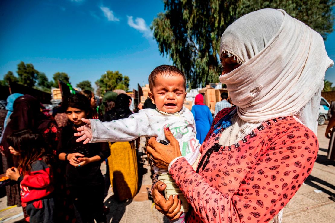 Displaced Syrians, who fled their homes in the border town of Ras al-Ain, receive humanitarian aid.