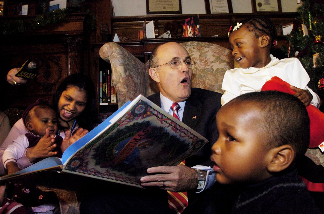 Giuliani reads "The Night Before Christmas" to children while visiting an orphanage in New York in December 2004.