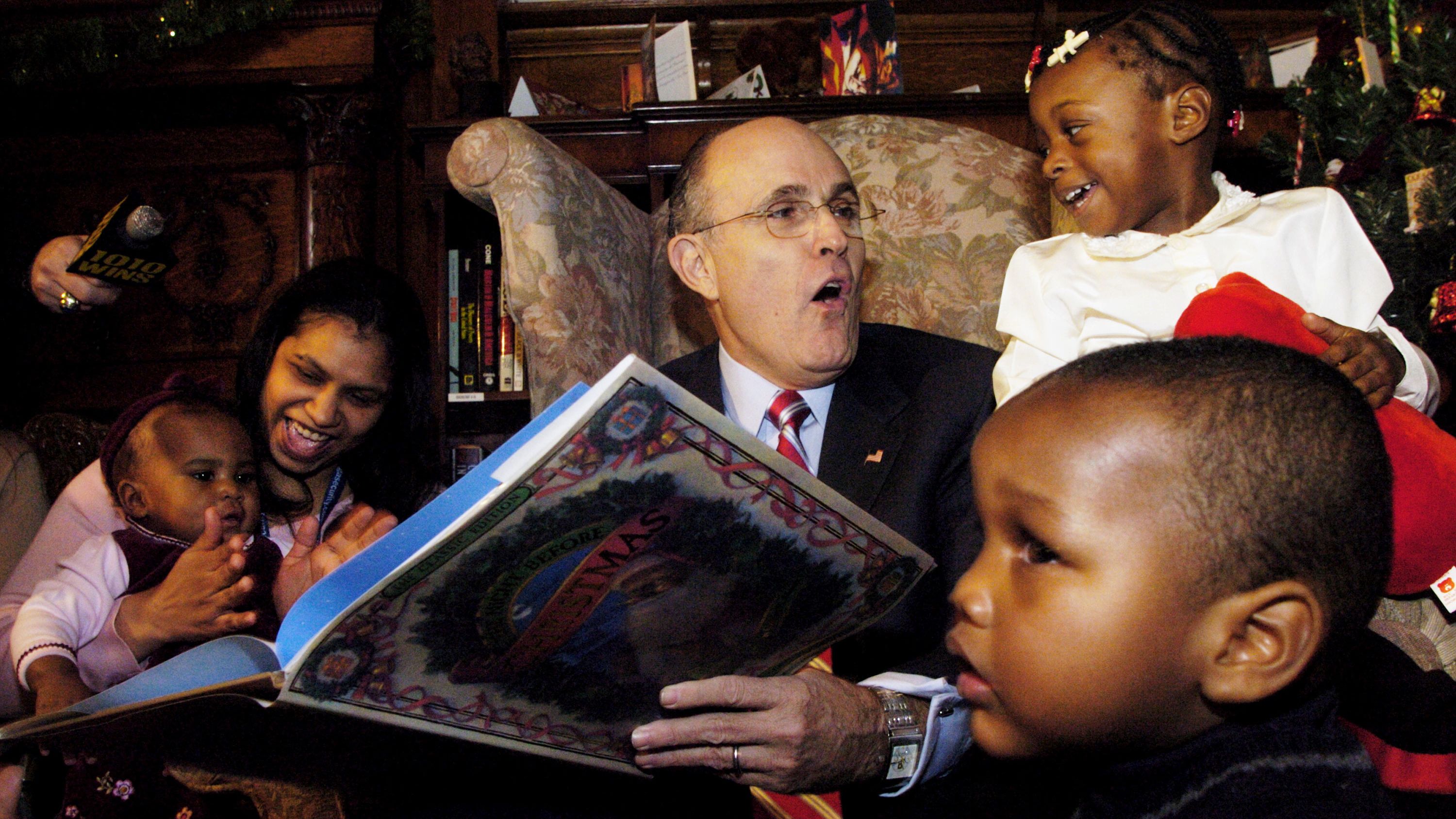 Giuliani reads "The Night Before Christmas" to children while visiting an orphanage in New York in December 2004.