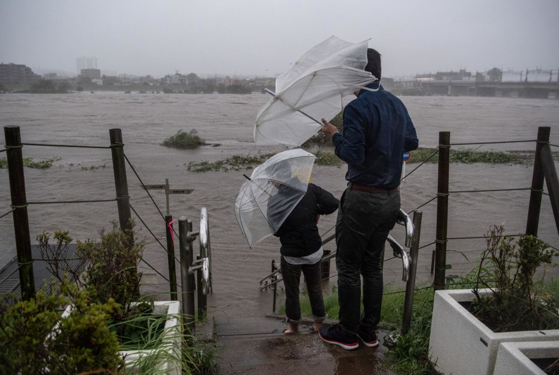 People look at the flooded Tama River during Typhoon Hagibis on October 12, 2019 in Tokyo, Japan.