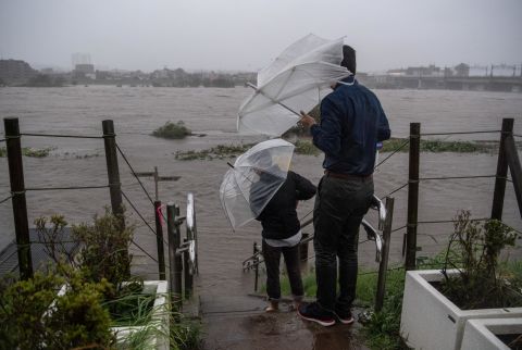 People look at the flooded Tama River in Tokyo on October 12.