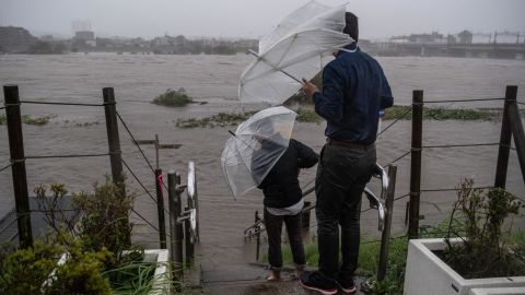 People look at the flooded Tama River during Typhoon Hagibis on October 12, 2019 in Tokyo, Japan.