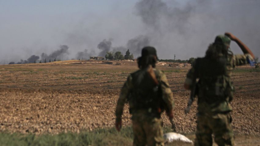 Turkish-backed Syrian fighters watch as smoke billows from the Syrian border town of Tal Abyad on October 12, 2019, as Turkey and its allies continue their assault on Kurdish-held border towns in northeastern Syria. - Ankara stepped up its assault on Kurdish-held border towns in northeastern Syria, defying mounting threats of international sanctions, even from Washington. (Photo by Bakr ALKASEM / AFP) (Photo by BAKR ALKASEM/AFP via Getty Images)