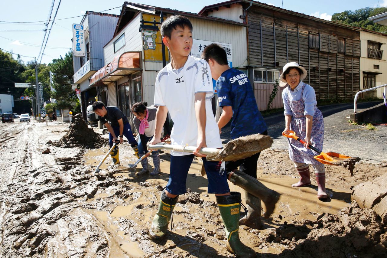 Students and residents scoop dirt and mud on October 13 as the town of Marumori, Japan, is flooded from the typhoon, which made landfall on Saturday.
