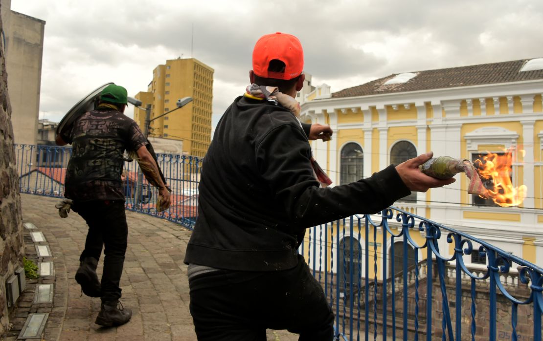 Demonstrators throw a Molotov cocktail during of protests in Quito on Saturday.