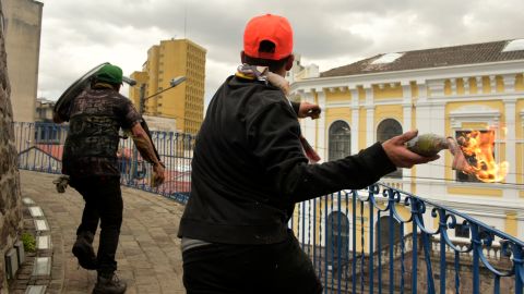 Demonstrators throw a Molotov cocktail during of protests in Quito on Saturday.
