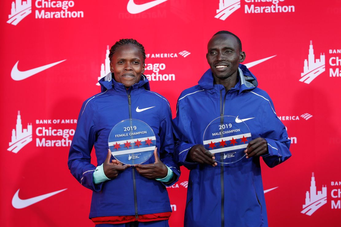 Kenya's Brigid Kosgei, left, and Lawrence Cherono smile as they hold their trophies. 