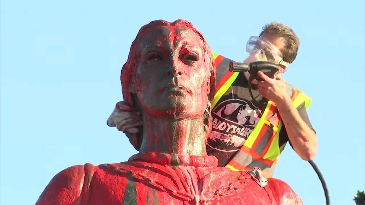 A worker sprays red paint off of a statue of Christopher Columbus on Sunday in San Francisco.