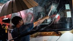 HONG KONG, CHINA - OCTOBER 13: A pro-democracy protester attempts to break a tourist bus front windows in Mongkok district on October 13, 2019 in Hong Kong, China. Hong Kong's government invoked emergency powers last week to introduce an anti-mask law which bans people from wearing masks at public assemblies as the city remains on edge with the anti-government movement entering its fourth month. Protesters in Hong Kong continue to call for Chief Executive Carrie Lam to meet their remaining demands since the controversial extradition bill was withdrawn, which includes an independent inquiry into police brutality, the retraction of the word riot to describe the rallies, and genuine universal suffrage, as the territory faces a leadership crisis.