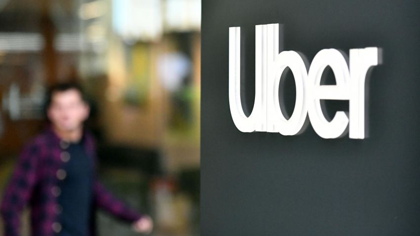 An Uber logo is seen on a sign outside the company's headquarters location as people protest nearby in San Francisco, California on May 8, 2019. - One of the early promises of the ride-hailing era ushered in by Uber and Lyft was that the new entrants would complement public transit, reduce car ownership and help alleviate congestion. But a new study on San F