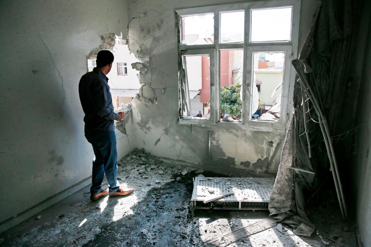 A person inspects damage to a building in Akcakale, Turkey, on Sunday, October 13. The building was damaged by a mortar fired from inside Syria.