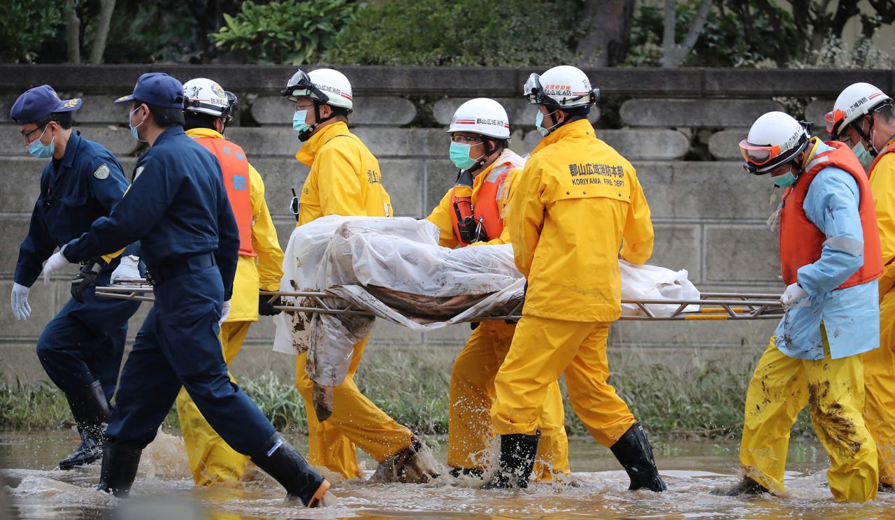 Police officers and fire fighters carry a dead body on a street after the flood in Koriyama City, Fukushima Prefecture on Monday.