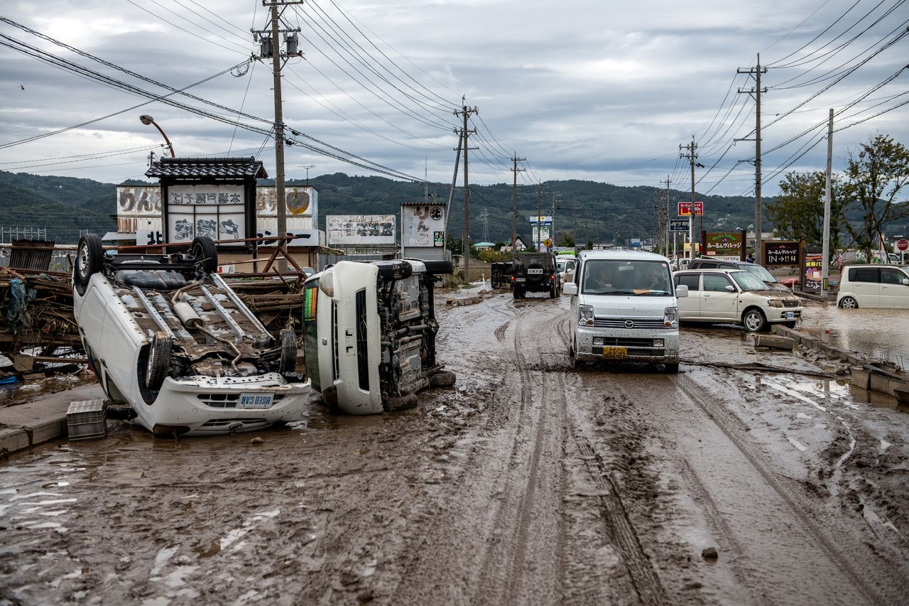A car passes overturned vehicles in an area affected by flooding on October 14 in Nagano, Japan.
