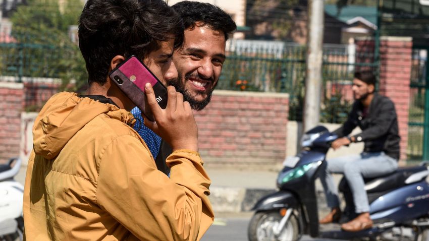A youth looks on as another one speaks on a mobile phone in Srinagar on October 14, 2019, following Indian government's decision to restore mobile phones network in Indian-administered Kashmir. - Mobile phone networks were restored in Indian Kashmir on October 14 after a 72-day blackout, authorities said, but the internet remained off-limits for the region's some eight million people. (Photo by HABIB NAQASH / AFP) (Photo by HABIB NAQASH/AFP via Getty Images)