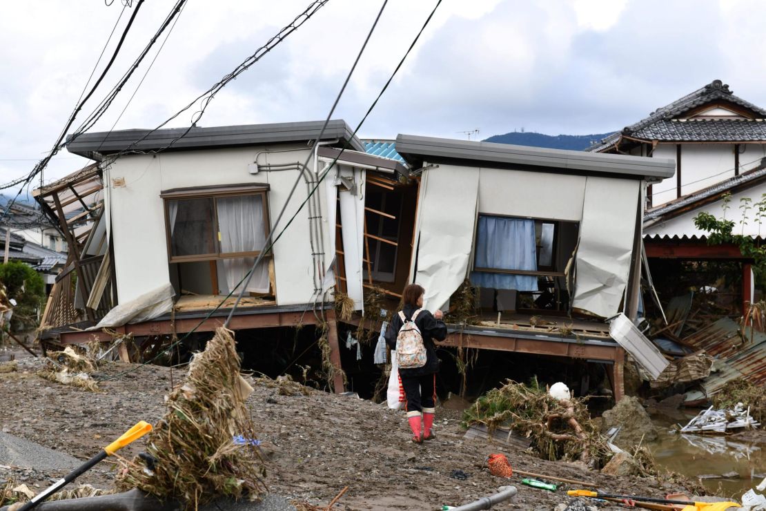 A woman looks at flood-damaged homes in Nagano on October 15, 2019, after high winds and torrential rain and triggered landslides and catastrophic flooding.