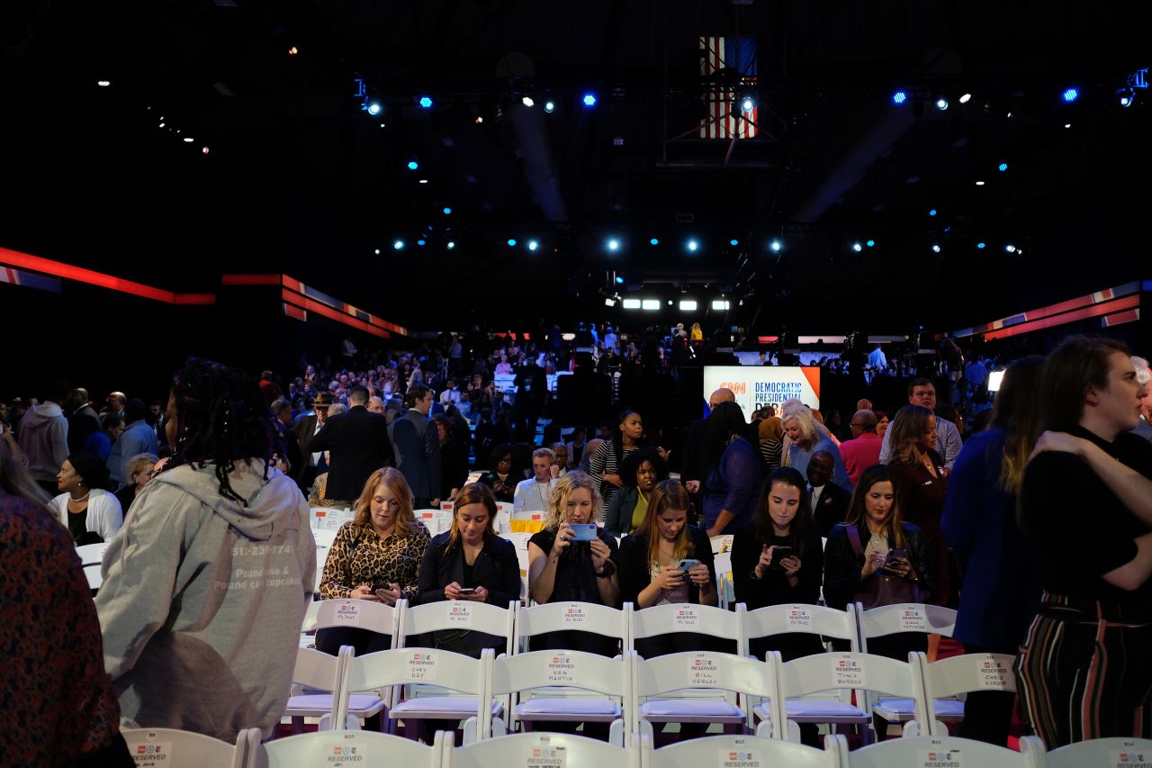 Audience members look at their cell phones in the hours before the debate.