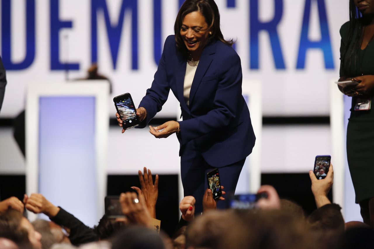 Harris holds a phone after taking a photo with the crowd.