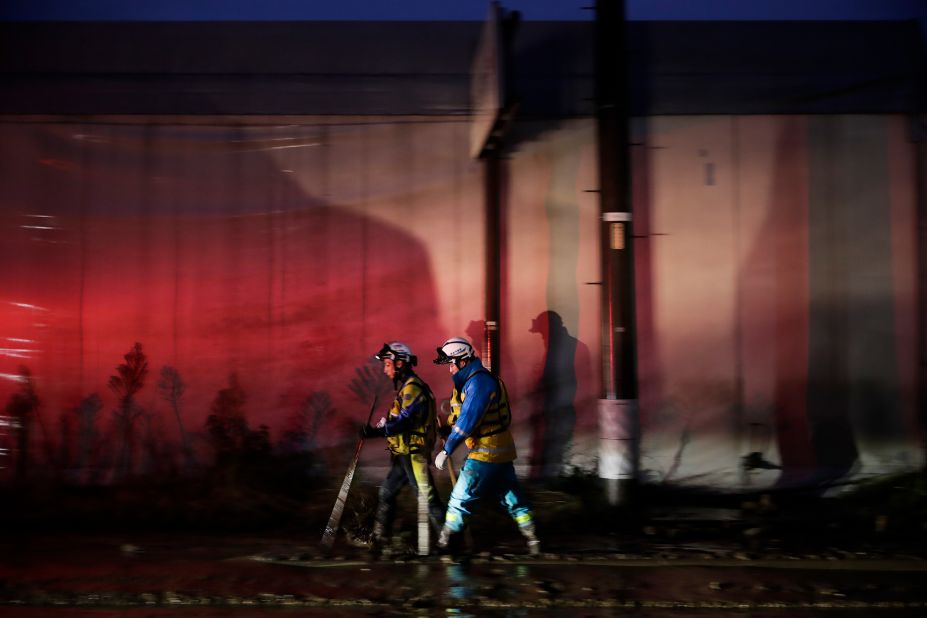 Two search and rescue team members walk along the mud-covered street Monday, October 14 in Hoyasu, Japan.
