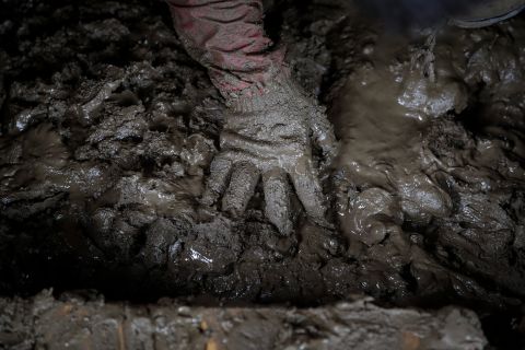 Yoshiki Yoshimura, 17, sifts through the mud for anything salvageable at his home destroyed by Typhoon Hagibis Tuesday. 
