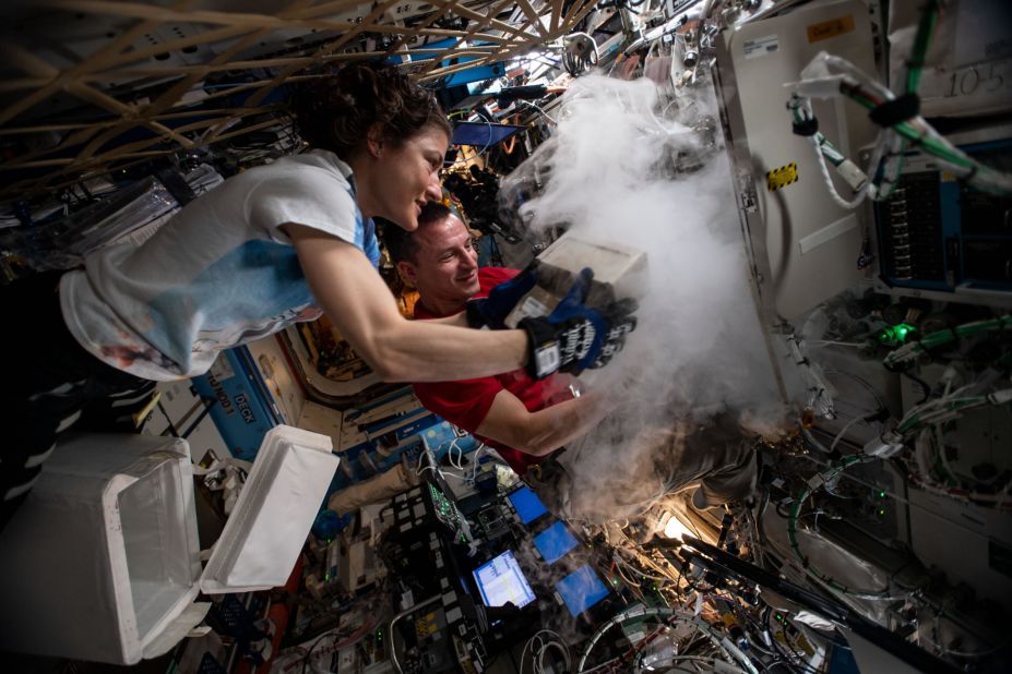 NASA astronauts Christina Koch and Andrew Morgan store research samples in a science freezer inside the U.S. Destiny laboratory module.