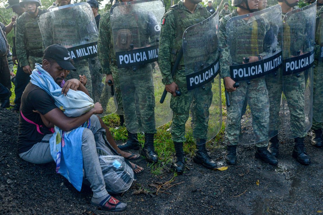 A migrant tends to a child while surrounded by members of the National Guard near Tuzantan, Mexico, on October 12.