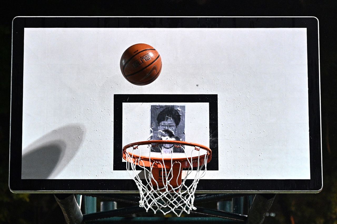 A protester shoots a basketball at a poster of Lam during a rally on Tuesday, October 15.