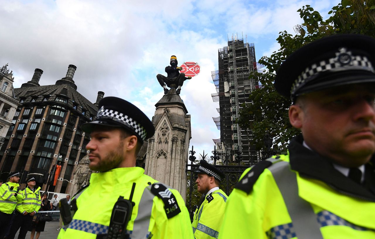 An Extinction Rebellion climate protester sits atop a fence pillar on the perimeter of the houses of parliament in London, on Tuesday October 15.