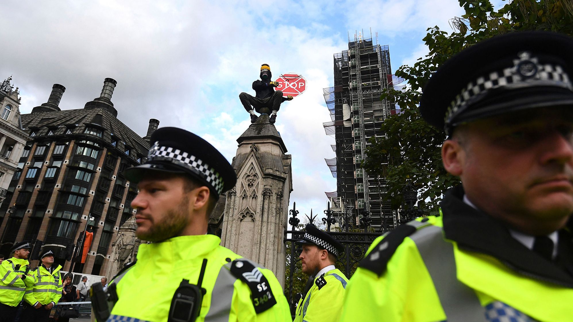 An Extinction Rebellion climate protester sits atop a fence pillar on the perimeter of the houses of parliament in London, on Tuesday October 15. 