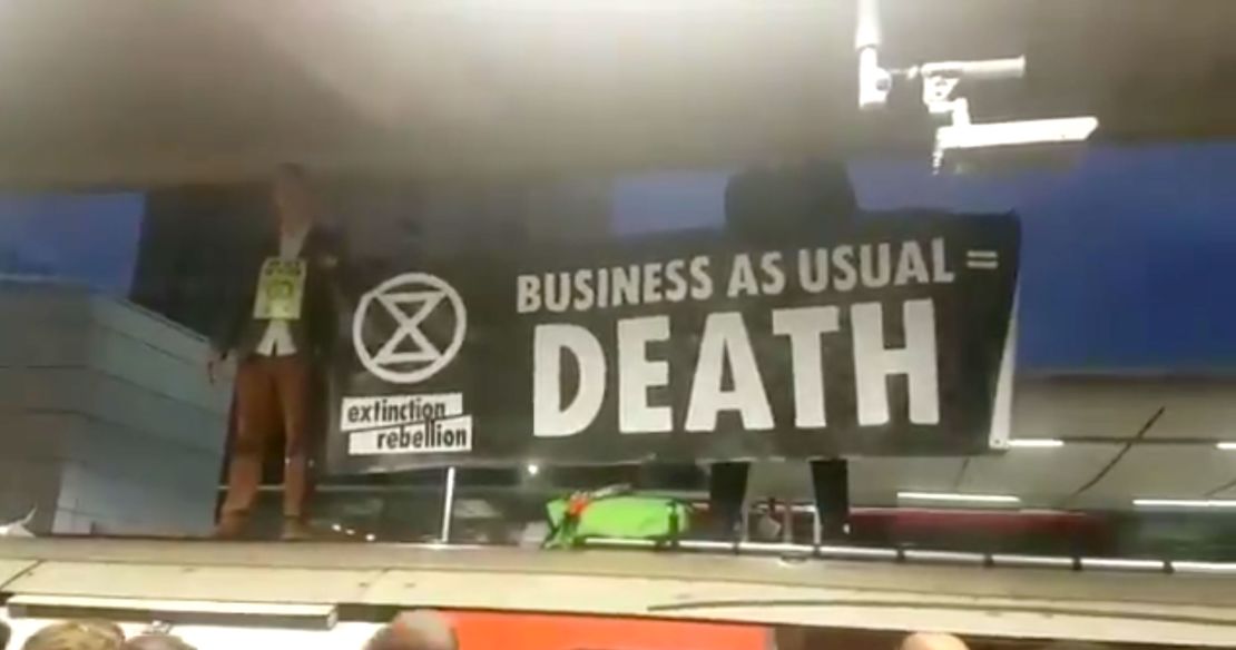 Extinction Rebellion protesters hold a sign that reads: "Business as usual = Death."