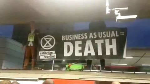 Extinction Rebellion protesters hold a sign that reads: "Business as usual = Death."