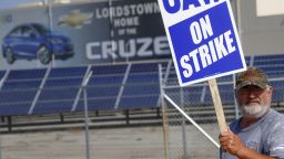 A picketer carries sign at one of the gates outside the closed General Motors automobile assembly plant, Monday, Sept. 16, 2019, in Lordstown, Ohio. (AP Photo/Keith Srakocic)