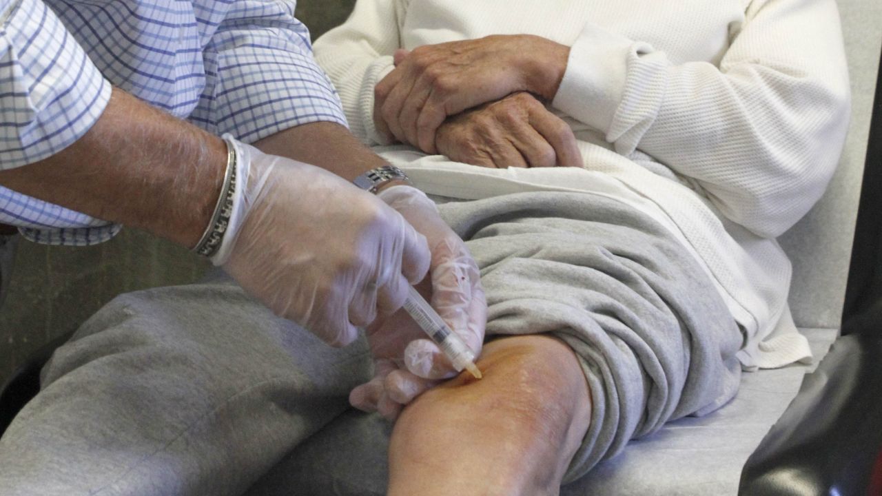 A doctor injects cortisone into a patient's knee.