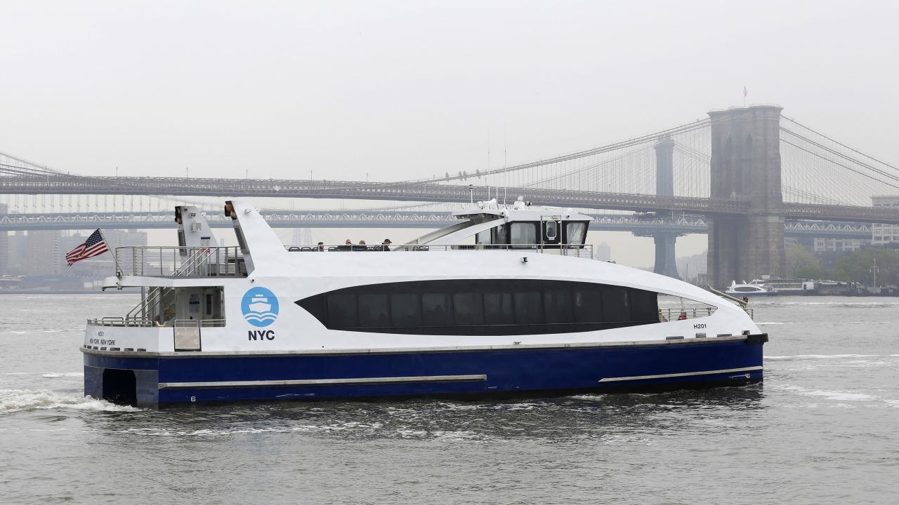 A New York City Ferry passes the Brooklyn Bridge.