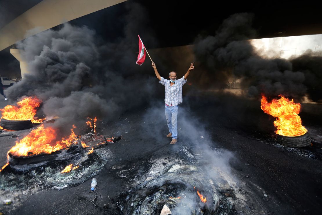 An anti-government protester makes a victory sign, as he holds a Lebanese national flag on Friday.