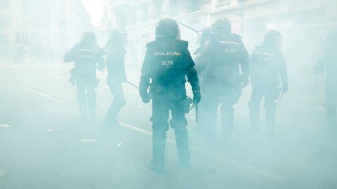 Spanish national police officers stand in the smoke as they protect the police headquarters in Barcelona.