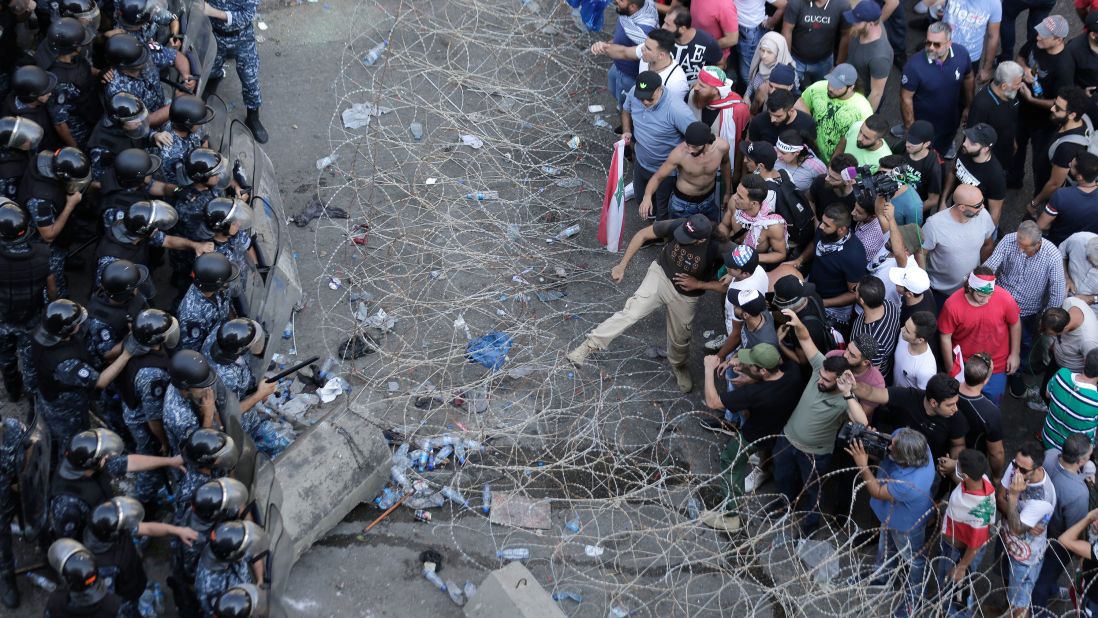 Police stand guard as anti-government protesters try to remove a barbed-wire barrier to advance toward government buildings on Saturday, October 19.