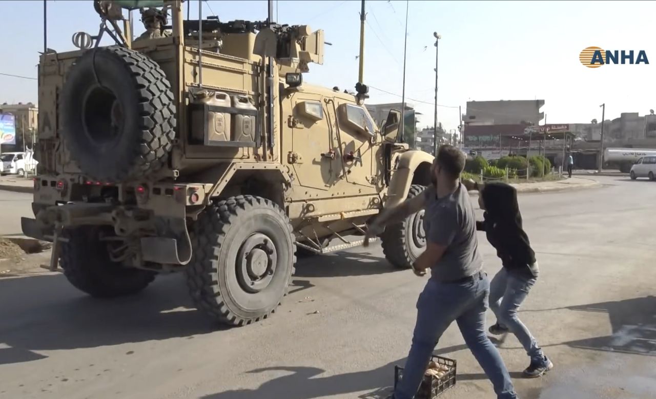 People angry over the US withdrawal hurl potatoes at American military vehicles as they pass through Qamishli on Monday, October 21. The image was taken from video provided by the Kurdish Hawar News Agency.