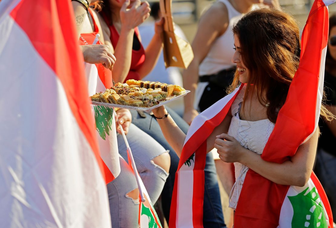 A Lebanese protester offers sweets to people during demonstrations Monday, north of Beirut.