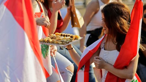 A Lebanese protester offers sweets to people during demonstrations Monday, north of Beirut.