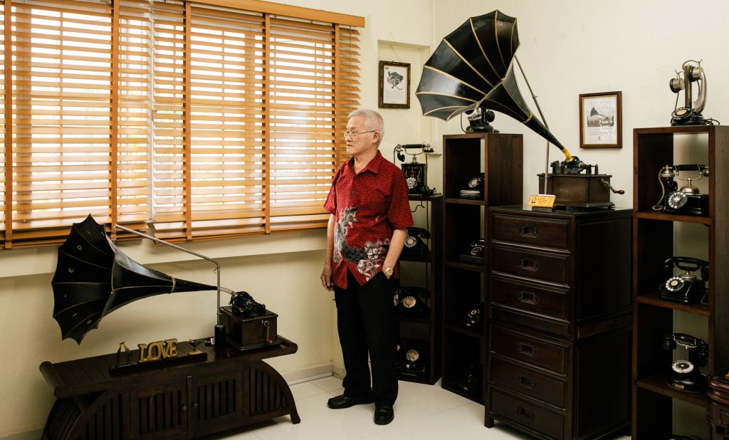 Harry Ang poses for a portrait with his collection of phonographs, gramophones and vintage phones in his home.
