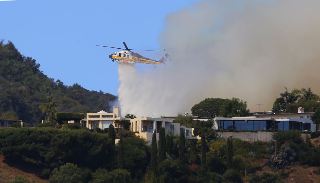 A helicopter makes a water drop as flames threaten homes on a ridgeline in the Pacific Palisades area of Los Angeles.