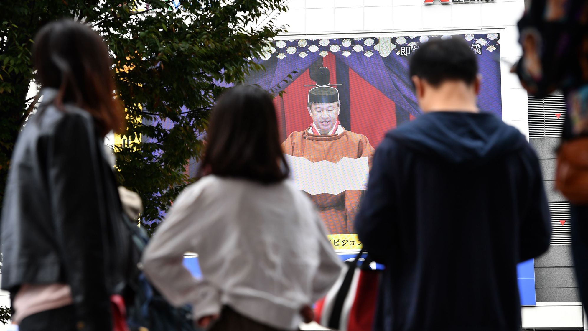 People watch Japan's Emperor Naruhito proclaim his enthronement during a live broadcast in Tokyo. 