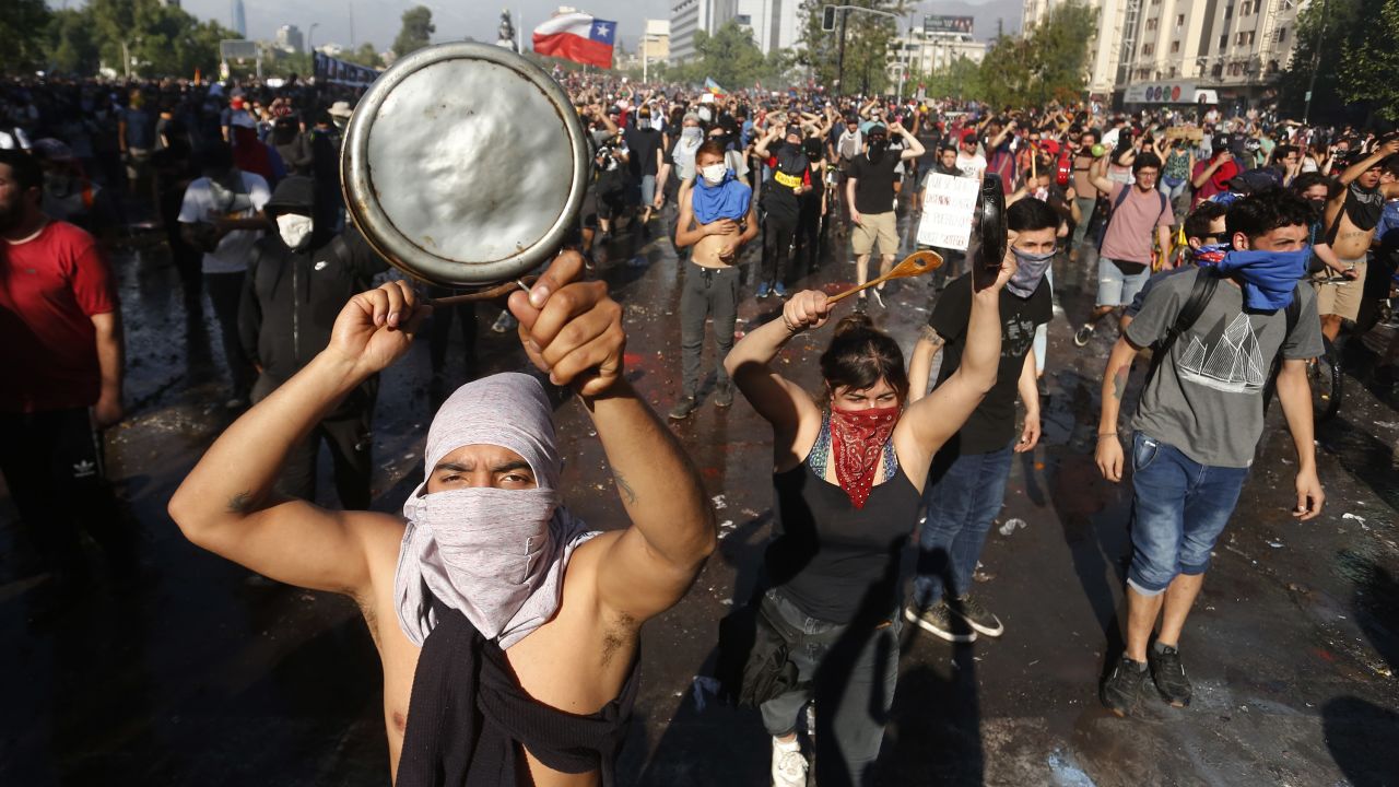 SANTIAGO, CHILE - OCTOBER 21: Demonstrators shouts slogans and display banners during a protest against Presidente Sebastian Pi?era on October 21, 2019 in Santiago, Chile. President Sebastian Pi?era suspended the 3.5% subway fare hike and declared the state of emergency for the first time since the return of democracy in 1990. Protests had begun on Friday and developed into looting and arson, generating chaos in Santiago, Valparaiso and a dozen other cities resulting in at least 8 dead.  (Photo by Marcelo Hernandez/Getty Images)