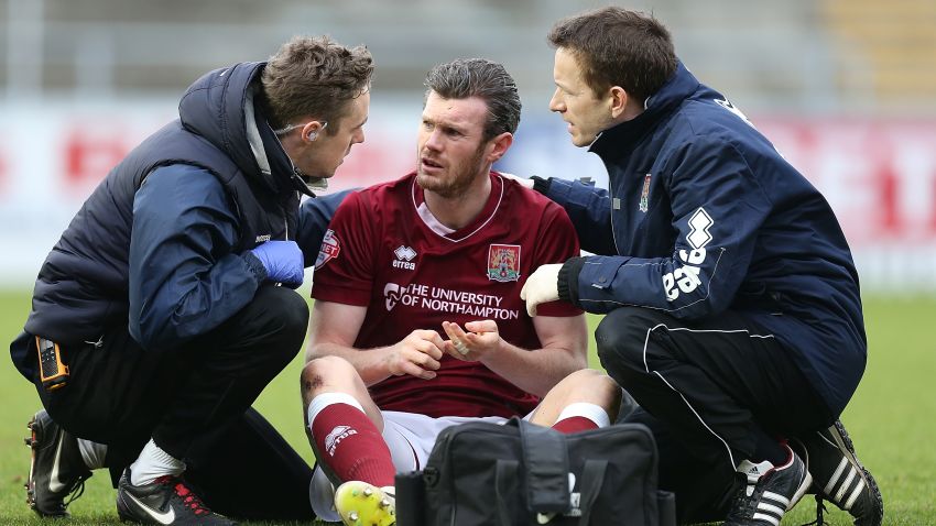 NORTHAMPTON, ENGLAND - FEBRUARY 06:  Zander Diamond of Northampton Town recieves treatment from physio Anders Braastad and Dr Andrew Odwell after a clash of heads which left him concussed during the Sky Bet League Two match between Northampton Town and York City at Sixfields Stadium on February 6, 2016 in Northampton, England.  (Photo by Pete Norton/Getty Images)