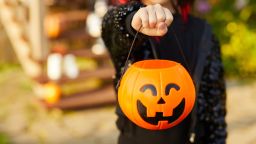 Closeup of unrecognizable little girl wearing Halloween costume and holding pumpkin basket in trick or treat season, copy space; Shutterstock ID 1499358104; Job: Design