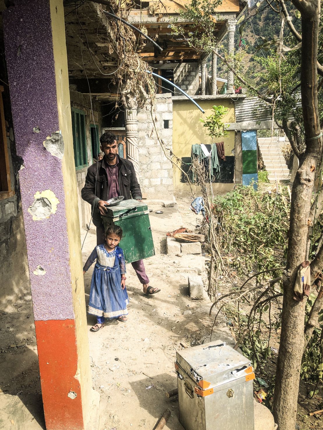 A little girl stands by her father as he clears rubbish in Jura, Neelum Valley, in Pakistani-administered Kashmir, on October 22, 2019.