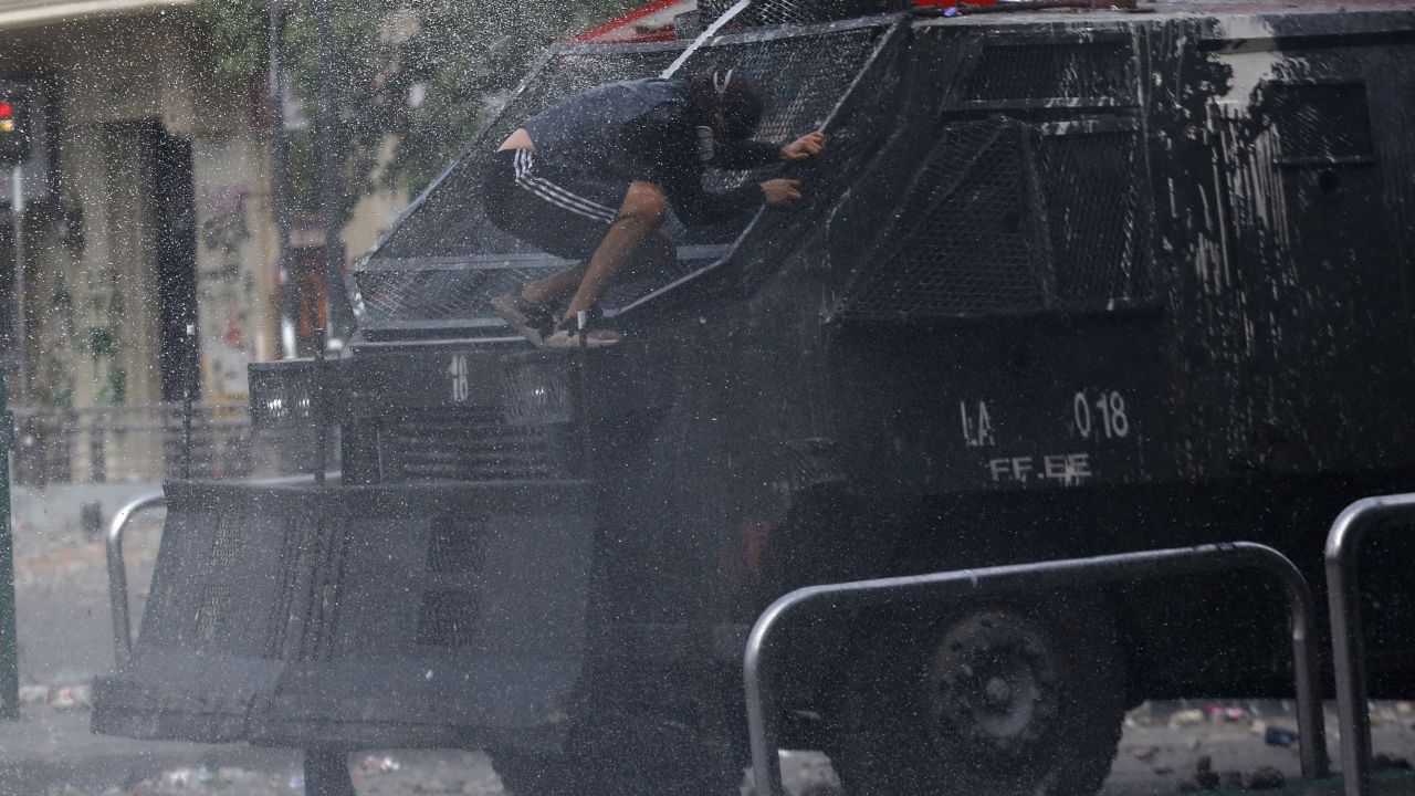 A demonstrator jumps in front of a police vehicle during the sixth day of protest against President Sebastian Pinera.