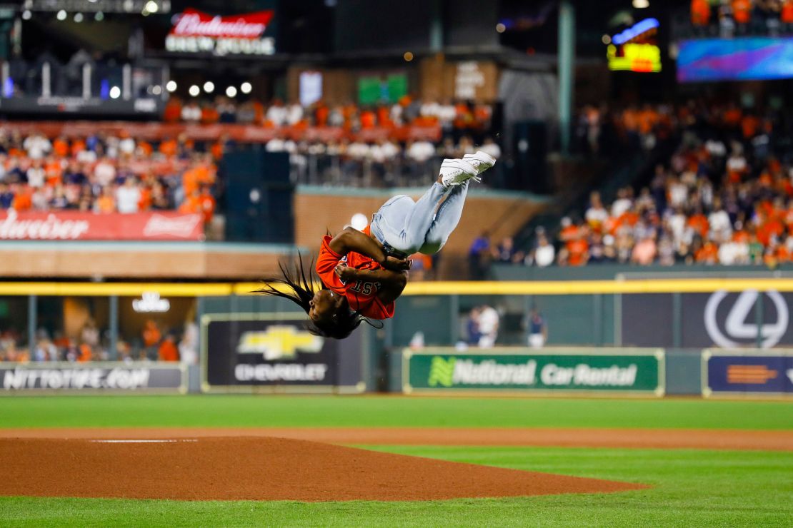 Gymnast Simone Biles performs a flip before throwing out the ceremonial first pitch prior to Game Two of the 2019 World Series.
