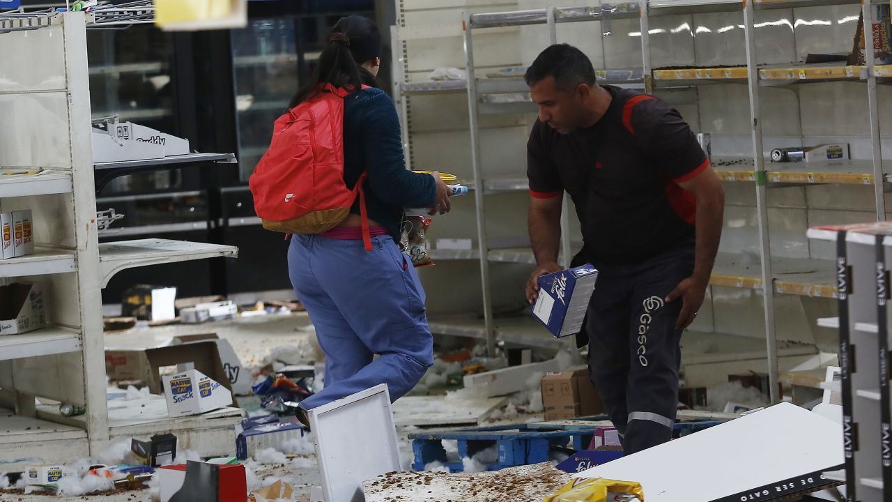 People take items from a looted supermarket in Santiago.